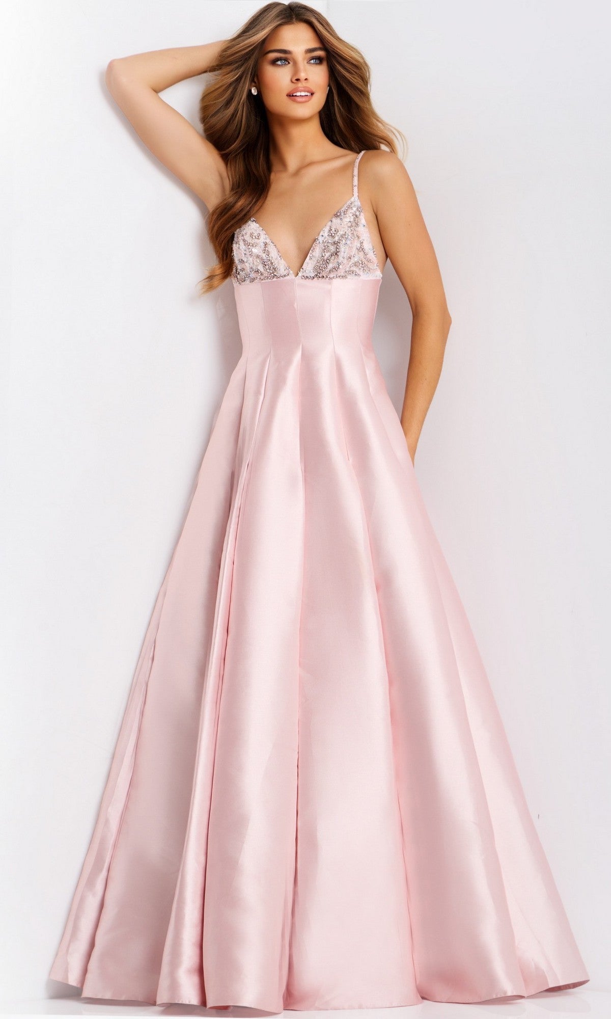 A woman stands against a plain background wearing the Jovani 48732 long prom dress in blush, featuring a fitted, embellished bodice and a flared skirt.